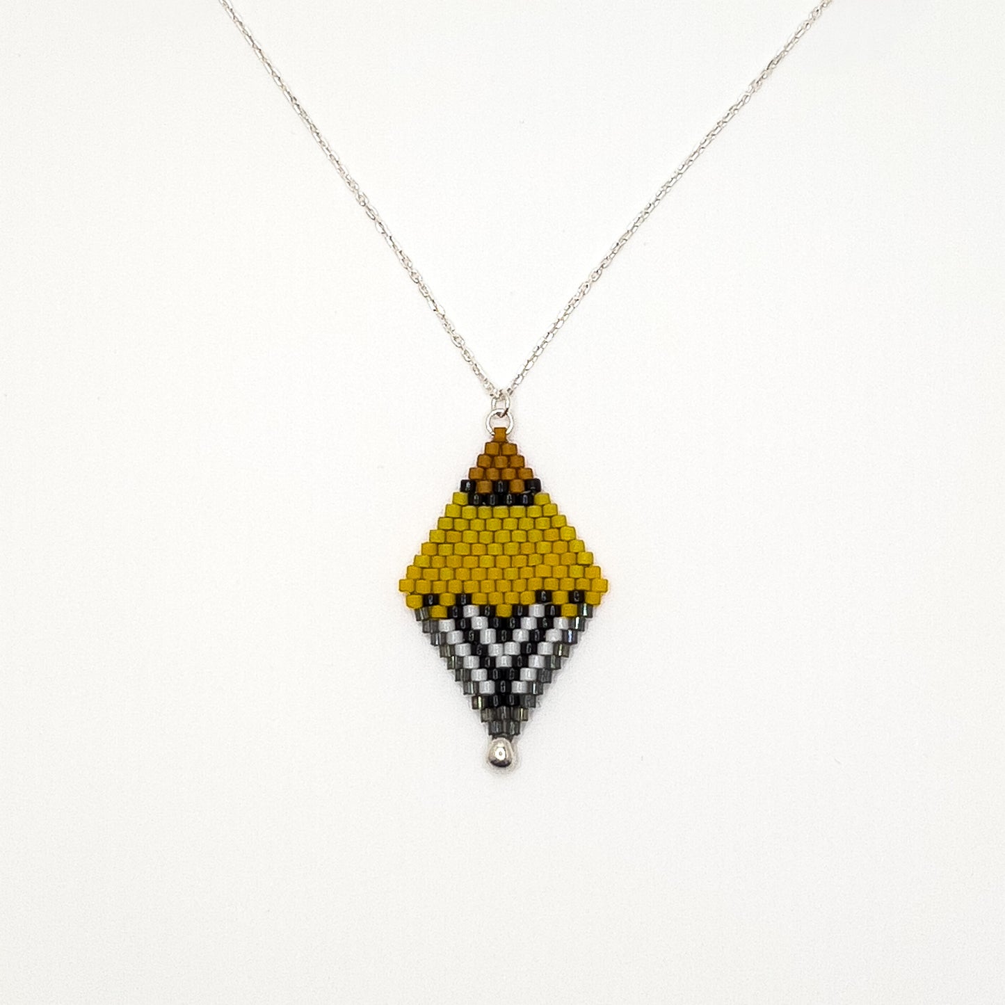Handcrafted beaded pendant with a sterling silver chain inspired by the American Goldfinch, featuring vibrant yellow, black, and white beads displayed on a white background.