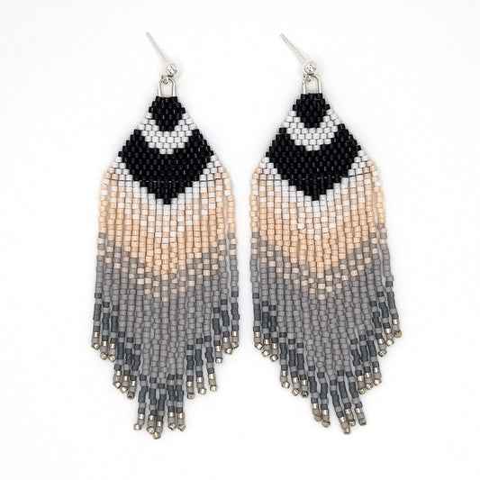 Handcrafted beaded earrings with sterling silver findings representing a Carolina Chickadee featuring a bold black and white V-shape at the top that resembles the bird’s distinctive head pattern, followed by soft cream and gray fringe laying on a white background.