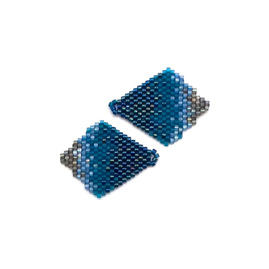 Close up of Indigo Bunting-inspired handcrafted beaded earring jackets displayed on white surface, showcasing a dark blue gradient pattern that transitions into softer blues and gray beads.