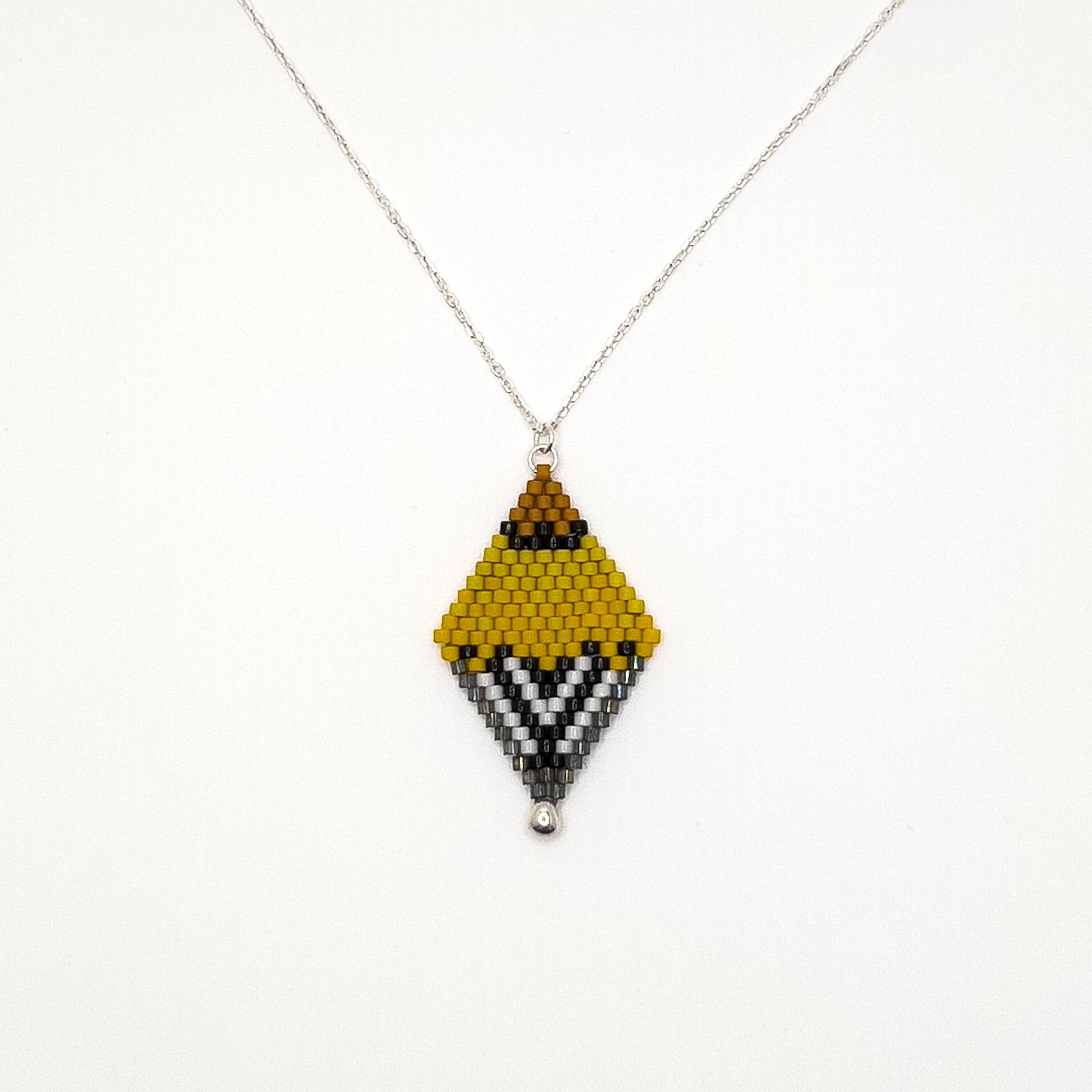 Handcrafted beaded pendant with a sterling silver chain inspired by the American Goldfinch, featuring vibrant yellow, black, and white beads displayed on a white background.