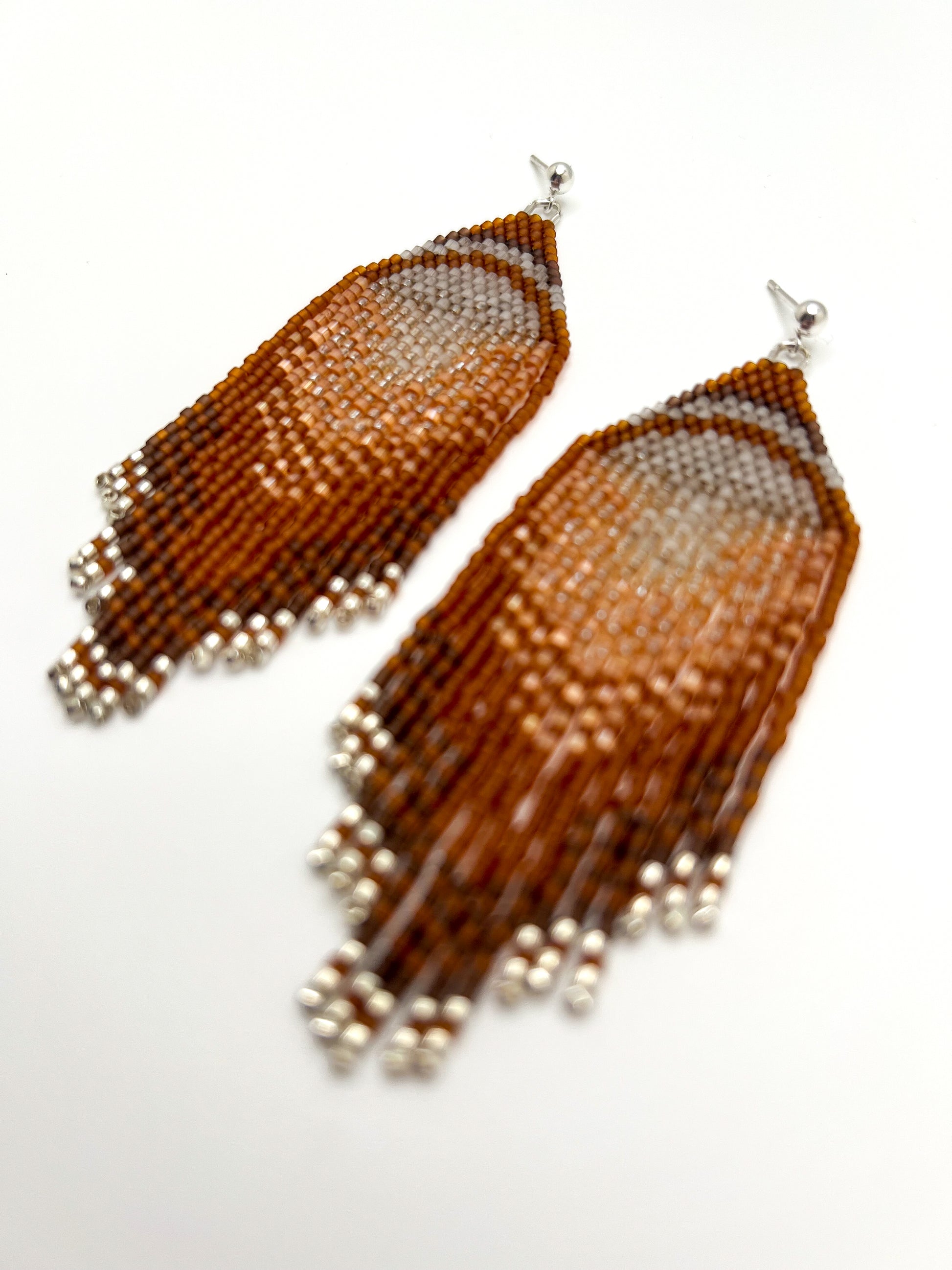 Pair of beaded earrings with a gradient design on a white background