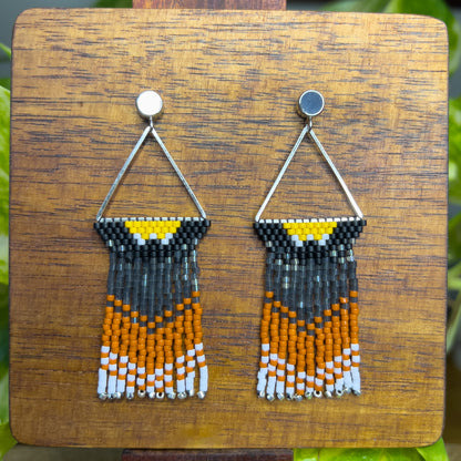 Handcrafted beaded earrings inspired by an American Robin displayed on a wooden surface, showcasing a triangular design with yellow, black, orange, and white beads in a vibrant, nature-inspired pattern.